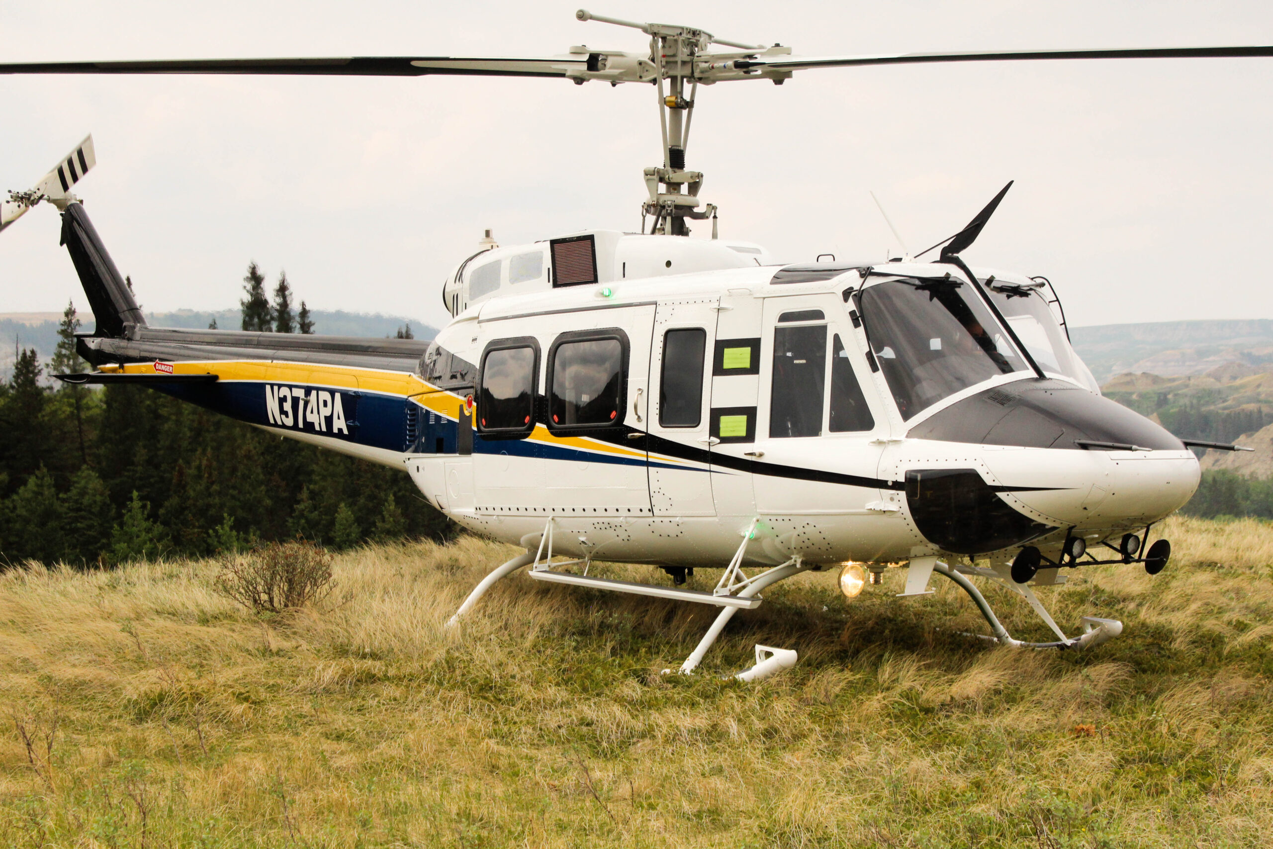 White, yellow and navy Eagle Single Helicopter landed on grass.